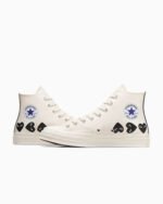 The Converse x Comme des Garçons PLAY Chuck 70 features classic Chuck Taylor styling with a playful twist. The quirky heart-and-eyes logo